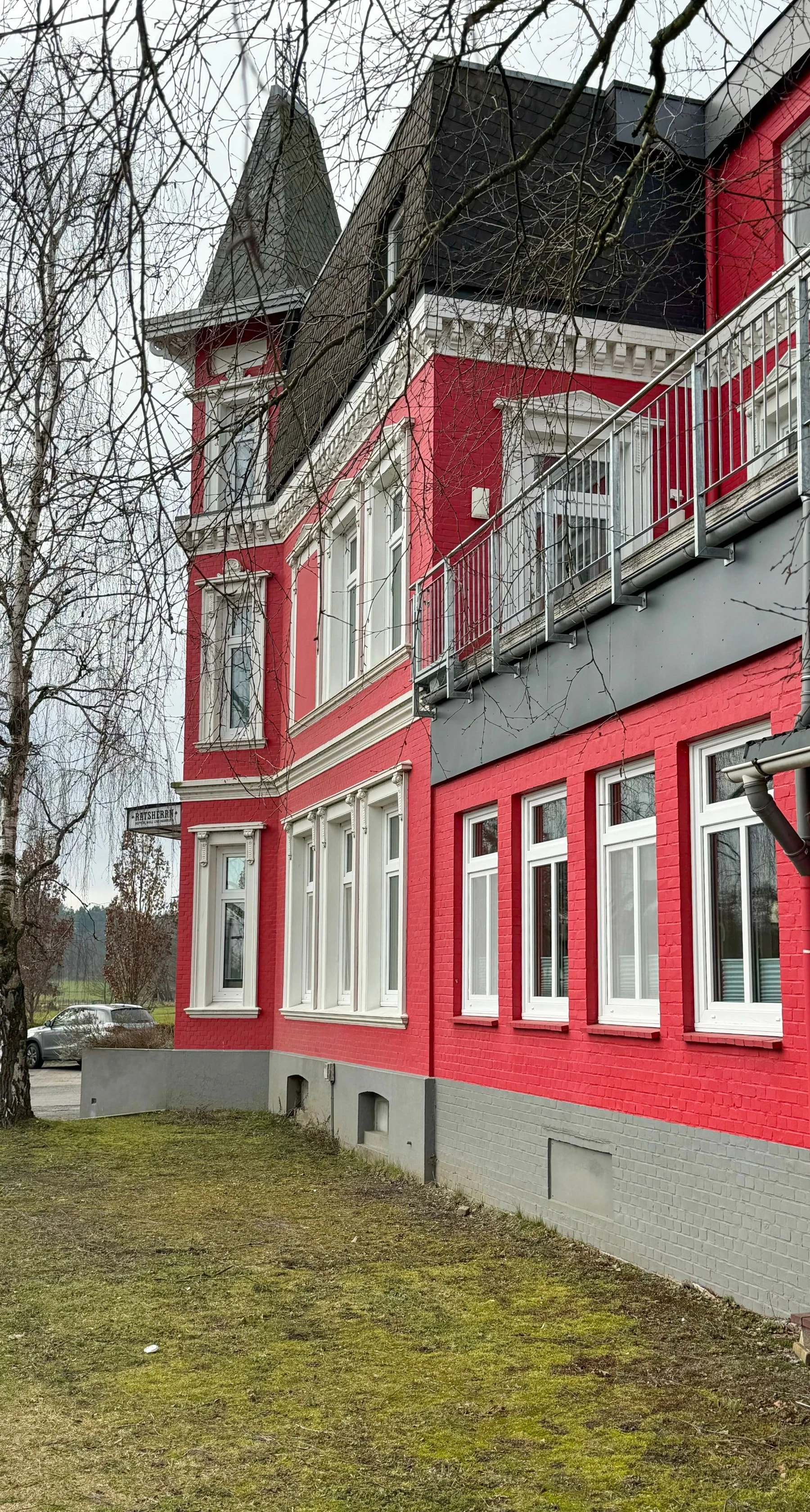 Frisch gestrichene Fassade einer Altbau-Villa in kräftigem Rot mit weiß abgesetzten Fensterrahmen